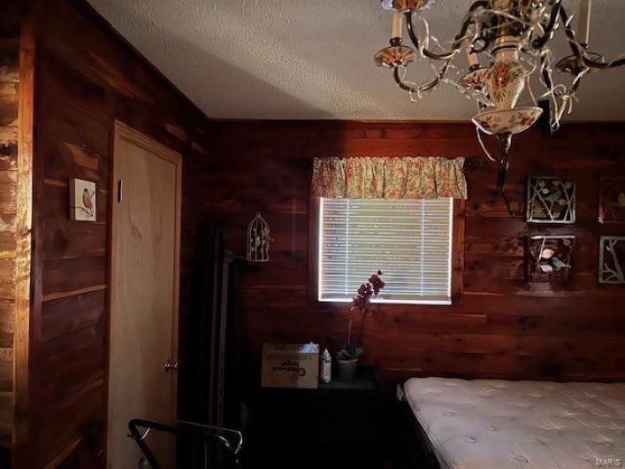 Bedroom with a textured ceiling and wooden walls