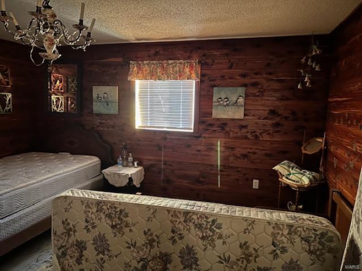 Bedroom featuring wood walls and a textured ceiling