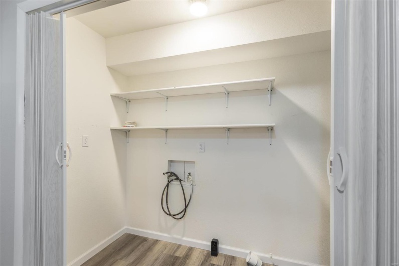 Washroom with hookup for a washing machine and wood-type flooring