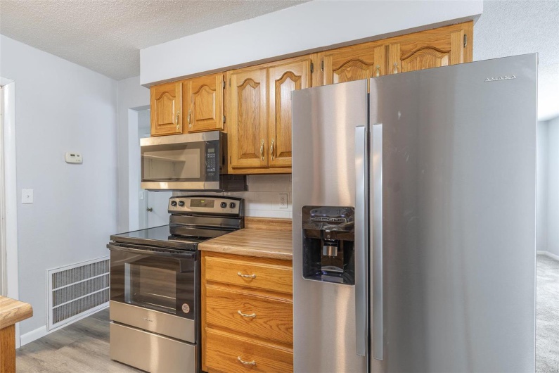 Kitchen featuring backsplash, stainless steel appliances, a textured ceiling, and light wood-type flooring