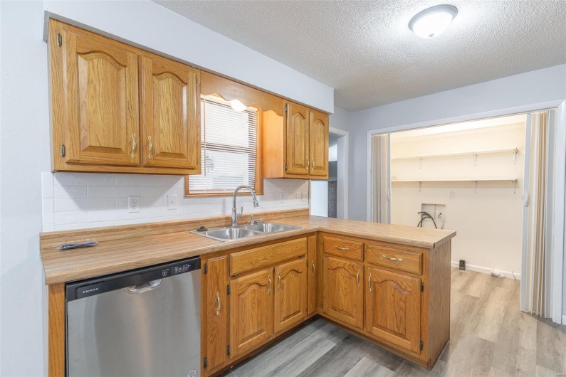 Kitchen featuring dishwasher, sink, a textured ceiling, light hardwood / wood-style floors, and kitchen peninsula