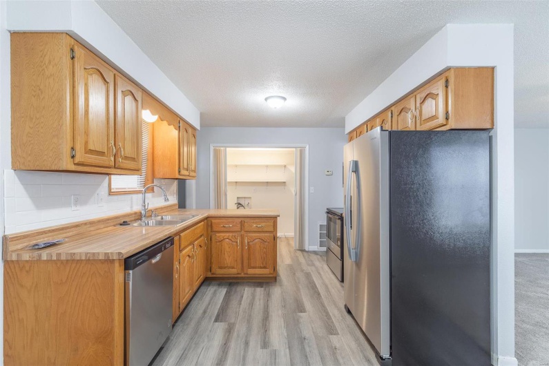 Kitchen with sink, light hardwood / wood-style flooring, a textured ceiling, appliances with stainless steel finishes, and kitchen peninsula