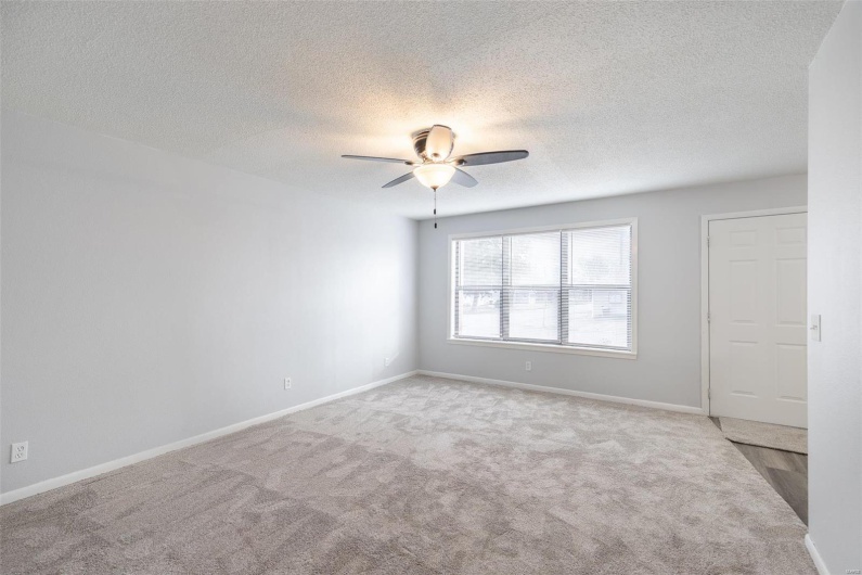 Empty room featuring a textured ceiling, light colored carpet, and ceiling fan