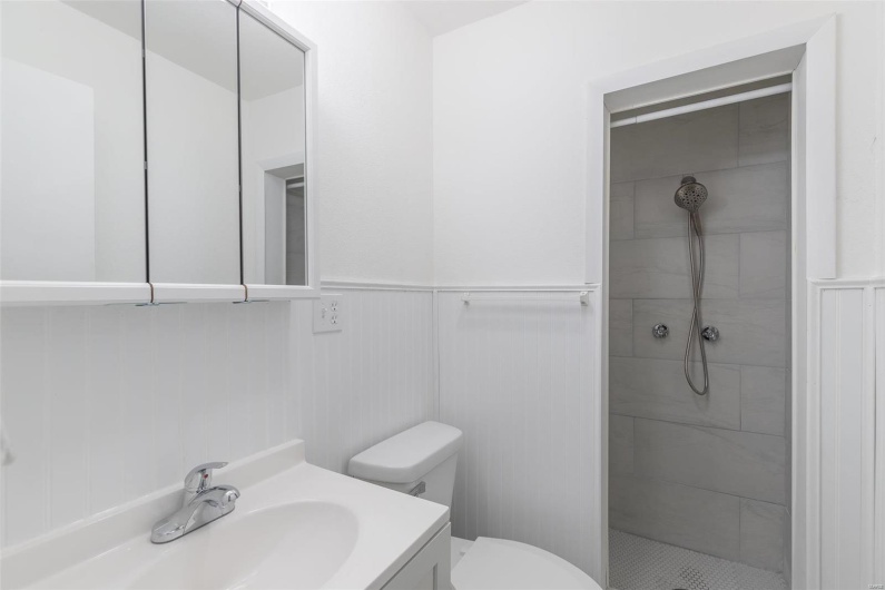 Bathroom with a tile shower, vanity, and toilet