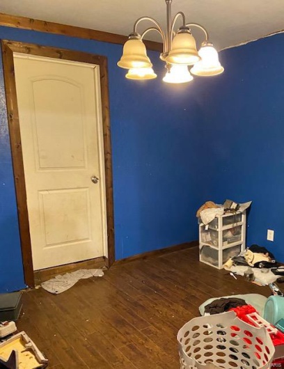 Unfurnished bedroom featuring dark hardwood / wood-style floors and a notable chandelier