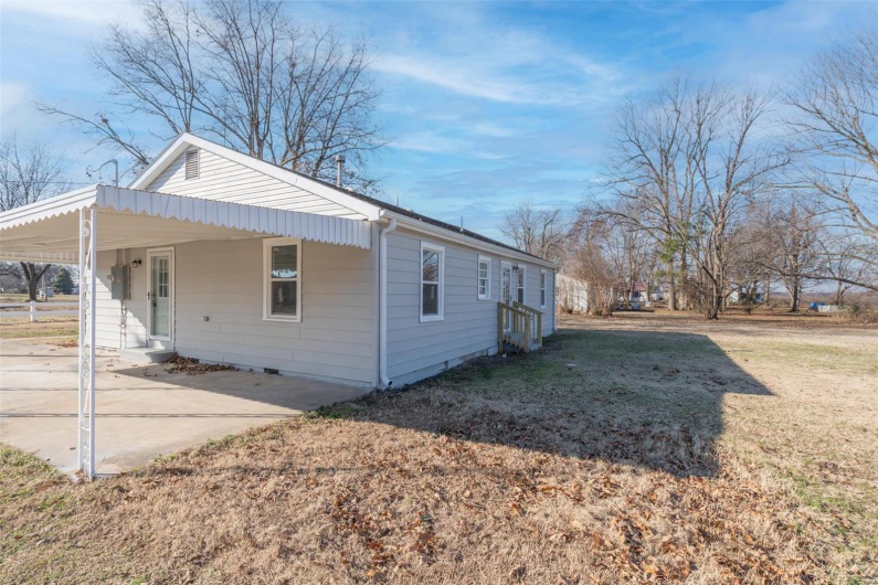 View of home's exterior with a lawn and a carport