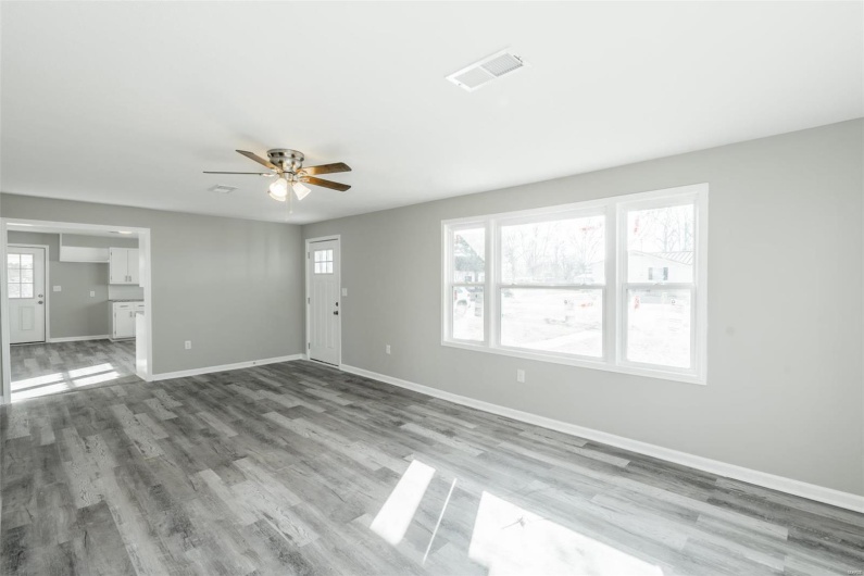 Unfurnished living room featuring ceiling fan, plenty of natural light, and hardwood / wood-style flooring