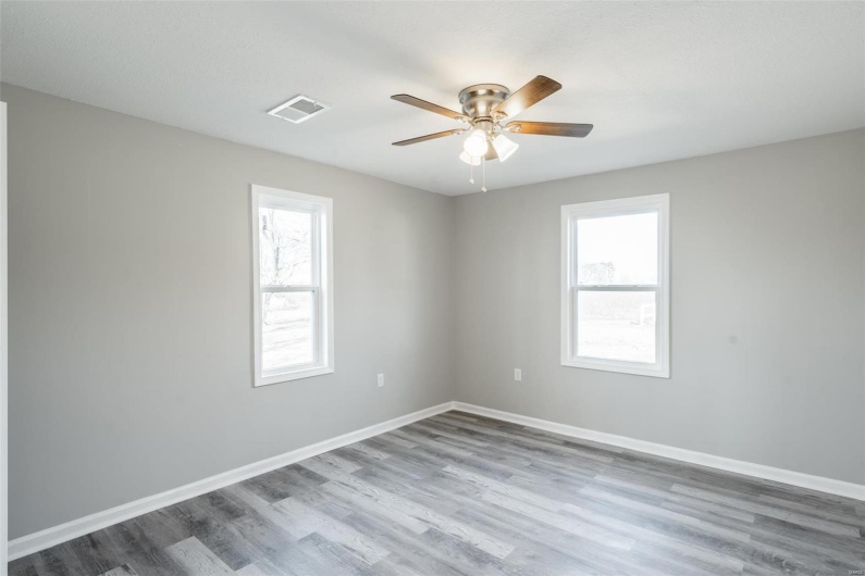 Unfurnished room with ceiling fan, a healthy amount of sunlight, and wood-type flooring