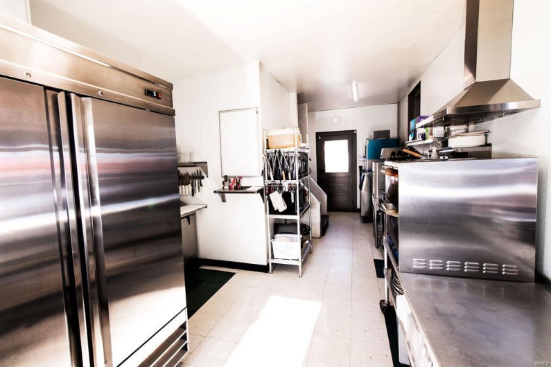 Kitchen with high end refrigerator, white cabinets, and wall chimney range hood