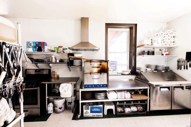 Kitchen with stainless steel counters, gas range, and exhaust hood