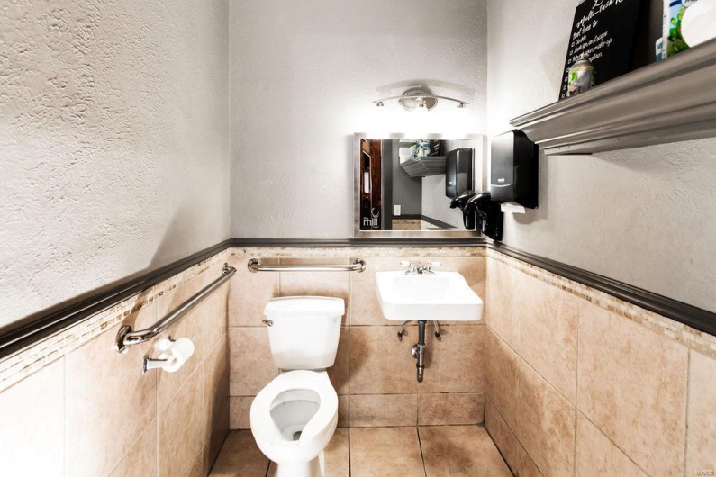 Bathroom featuring sink, toilet, and tile walls