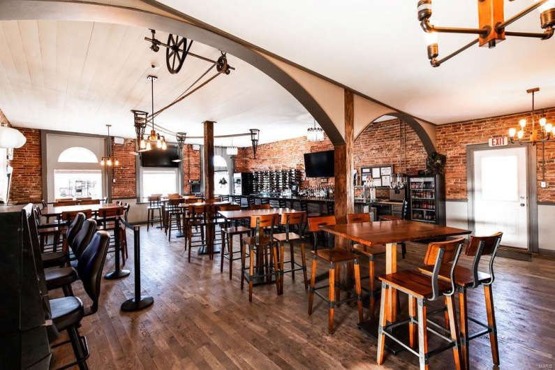 Dining space with dark wood-type flooring, brick wall, and a notable chandelier