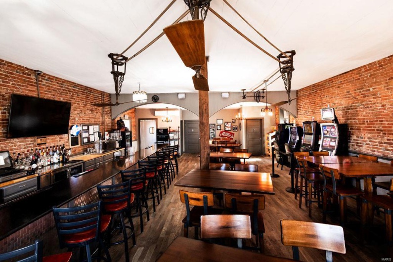 Bar with dark hardwood / wood-style floors, brick wall, and decorative light fixtures
