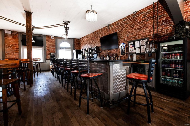 Bar featuring brick wall, dark hardwood / wood-style floors, and beverage cooler