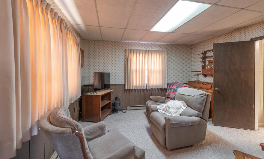 Living room with carpet, a baseboard radiator, and a drop ceiling