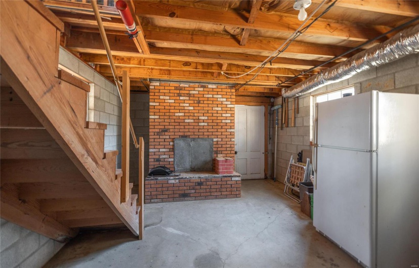 Basement featuring white fridge and a brick fireplace