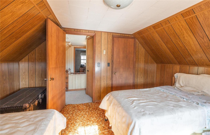 Bedroom with wood walls, carpet floors, and vaulted ceiling