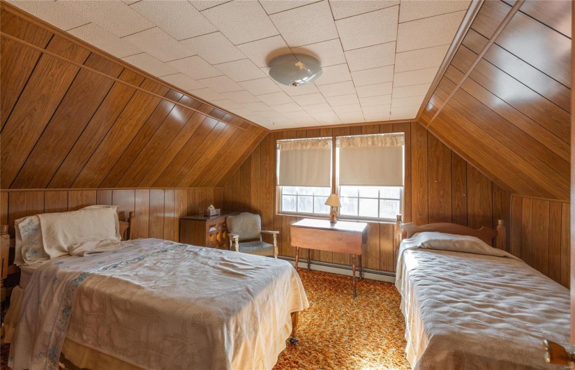 Bedroom with wood walls, carpet floors, and vaulted ceiling