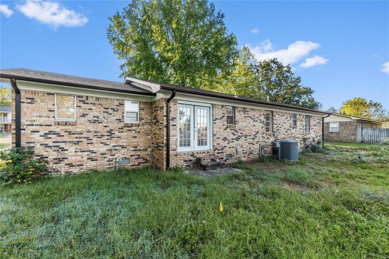 View of side of home featuring a lawn and central AC unit
