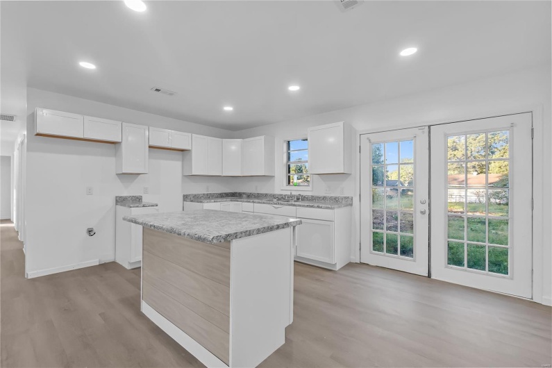 Kitchen with a wealth of natural light, white cabinetry, light hardwood / wood-style floors, and a center island