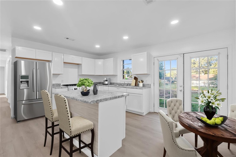 Kitchen with light hardwood / wood-style floors, white cabinets, a center island, and stainless steel fridge with ice dispenser