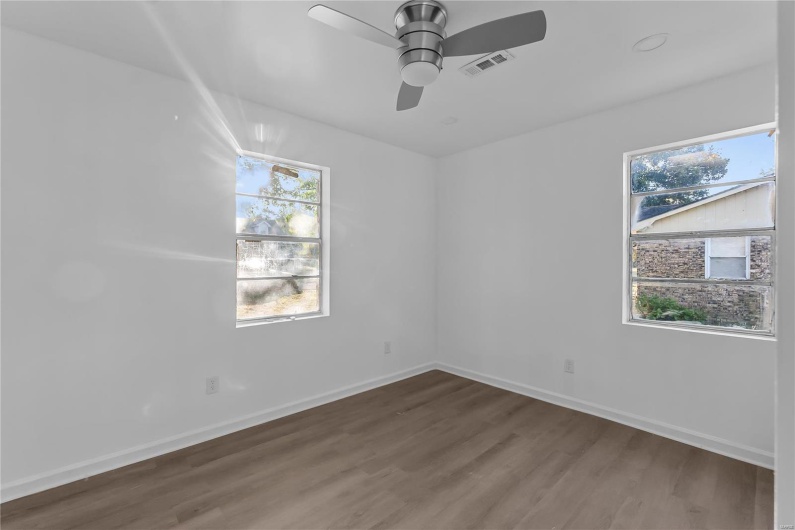 Unfurnished room with ceiling fan, dark wood-type flooring, and a wealth of natural light
