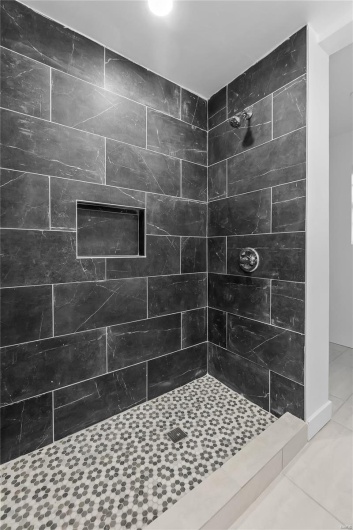 Bathroom with tiled shower and tile patterned flooring