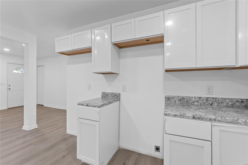Kitchen featuring light hardwood / wood-style flooring, white cabinetry, and light stone counters