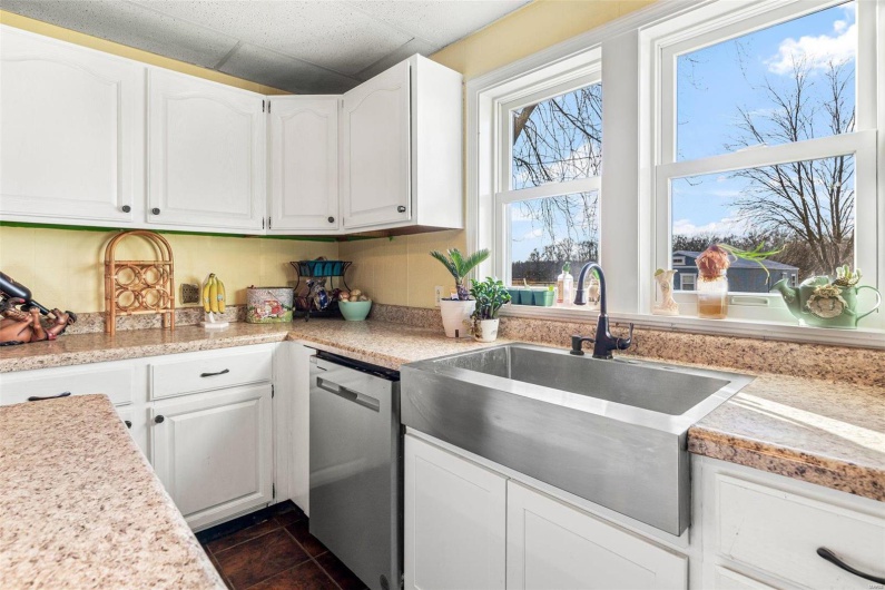 Kitchen with stainless steel dishwasher, white cabinets, and sink