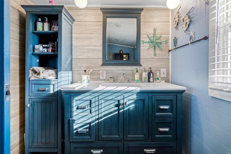 Bathroom with vanity, wooden walls, and vaulted ceiling