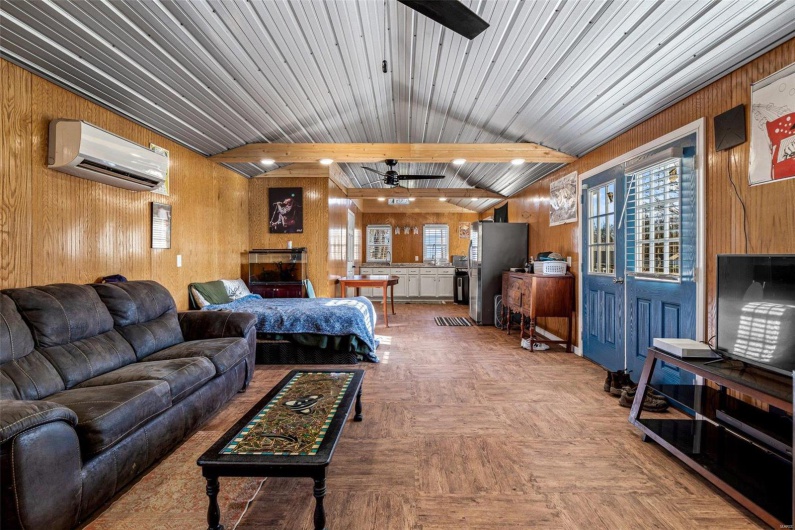 Living room featuring ceiling fan, wood walls, a wealth of natural light, and a wall mounted AC