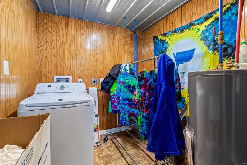 Washroom featuring washer / clothes dryer, wood walls, and water heater
