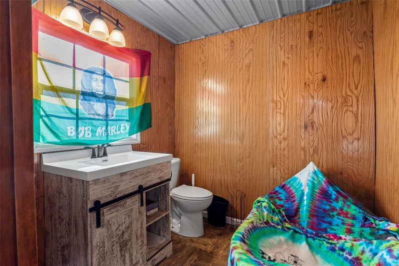 Bathroom featuring vanity, toilet, and wooden walls