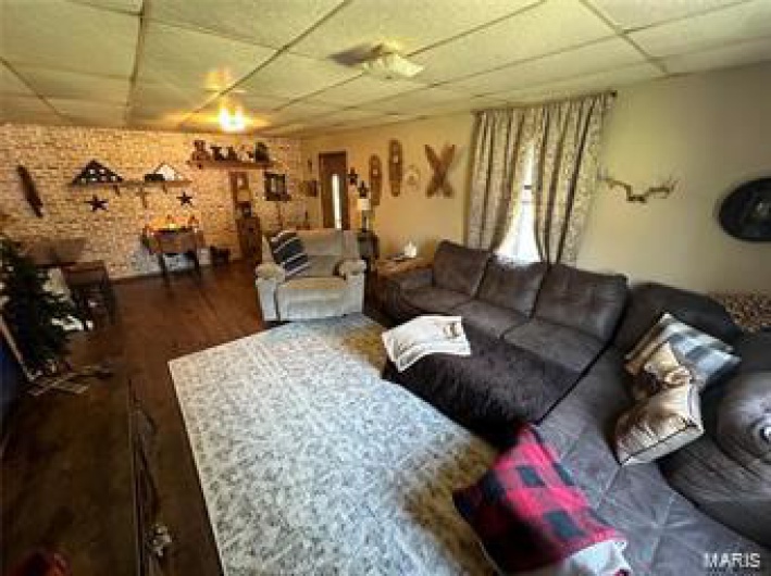 Living room featuring dark wood-type flooring and brick wall