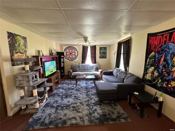Living room featuring a drop ceiling and ceiling fan
