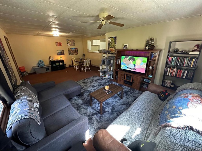 Carpeted living room with a drop ceiling and ceiling fan