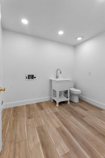 Laundry/half-bath with light hardwood/wood-style floors