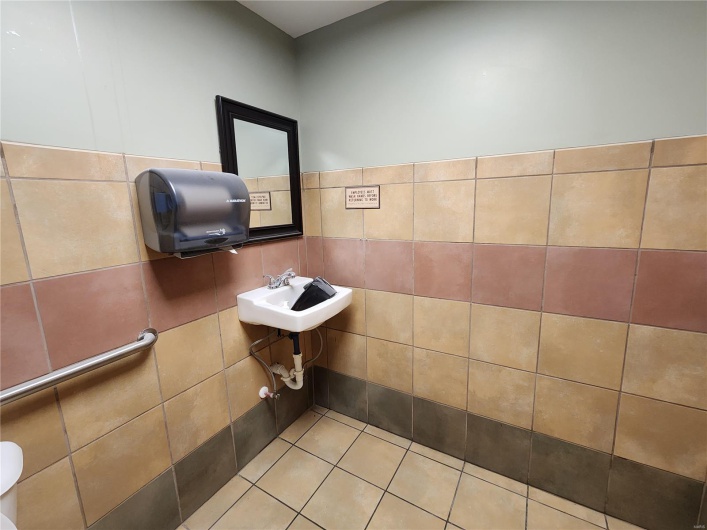 Bathroom with tile patterned flooring, tile walls, and sink