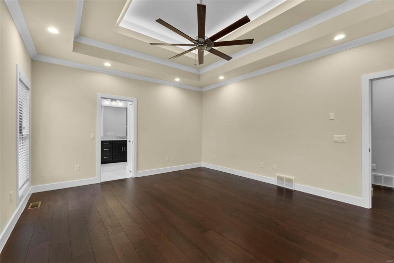 Unfurnished room featuring ceiling fan, dark hardwood / wood-style flooring, ornamental molding, and a tray ceiling