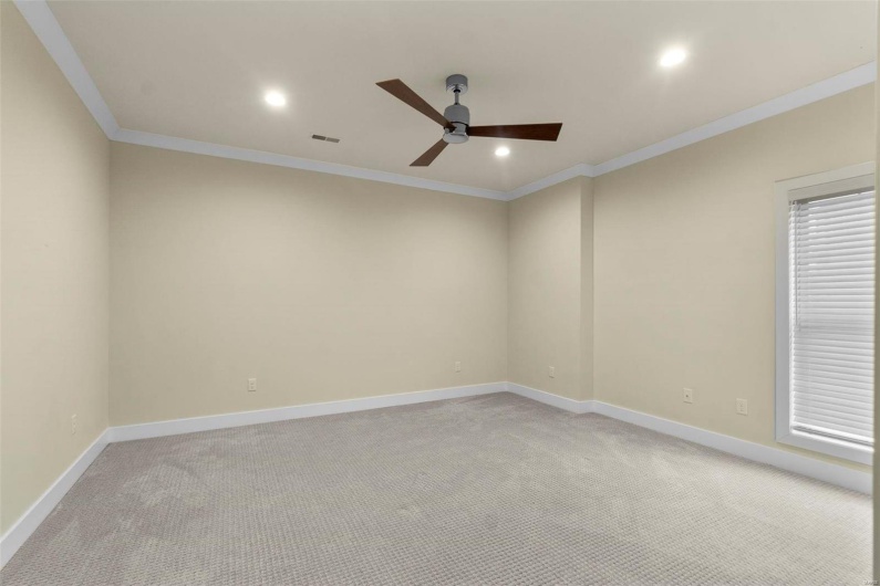 Spare room with ceiling fan, light colored carpet, and crown molding