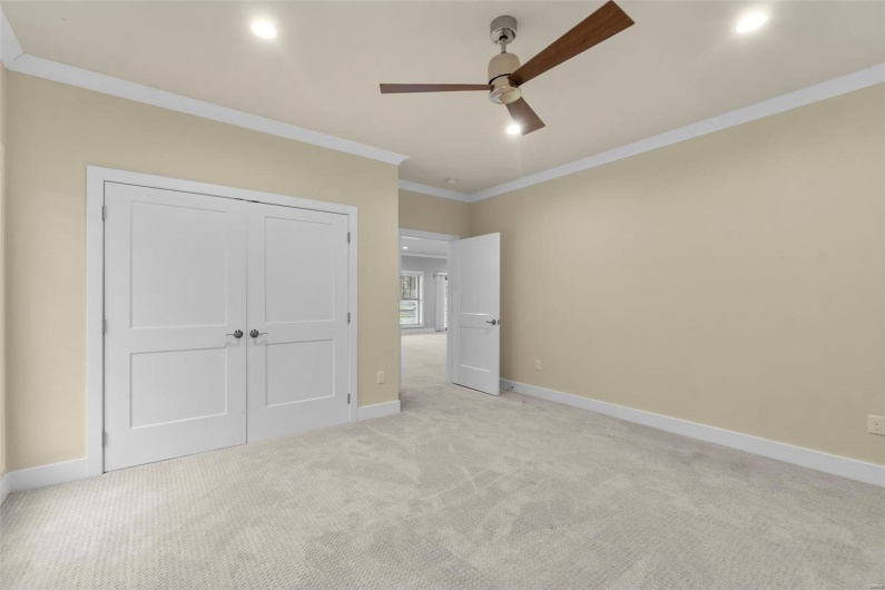 Unfurnished bedroom featuring light carpet, a closet, ceiling fan, and ornamental molding