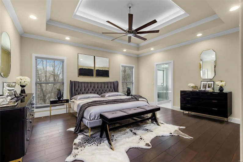 Bedroom with ceiling fan, ornamental molding, connected bathroom, and a tray ceiling