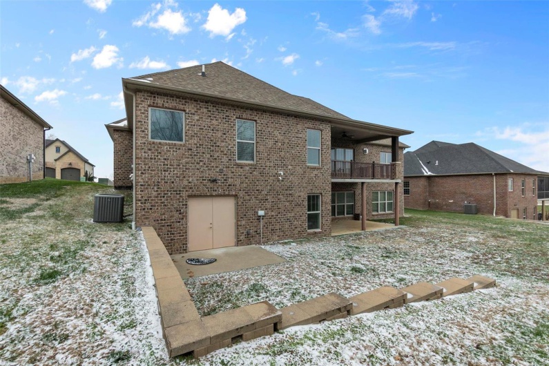 Snow covered rear of property with a balcony, cooling unit, and a patio
