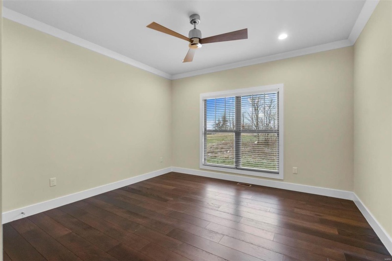 Spare room featuring dark hardwood / wood-style floors, ceiling fan, and crown molding