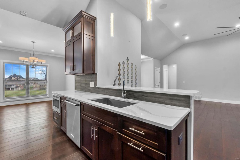 Kitchen with pendant lighting, dishwasher, backsplash, sink, and vaulted ceiling