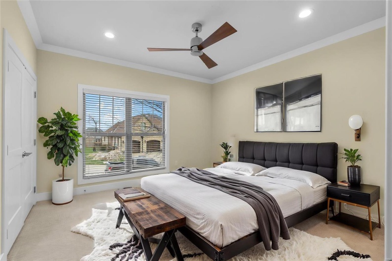 Carpeted bedroom with ceiling fan and ornamental molding