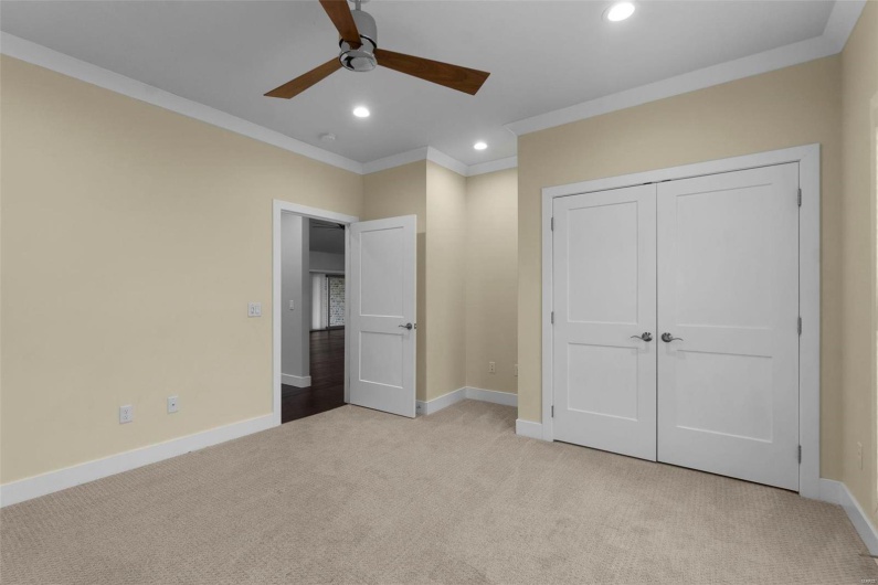 Unfurnished bedroom featuring light carpet, a closet, ceiling fan, and crown molding