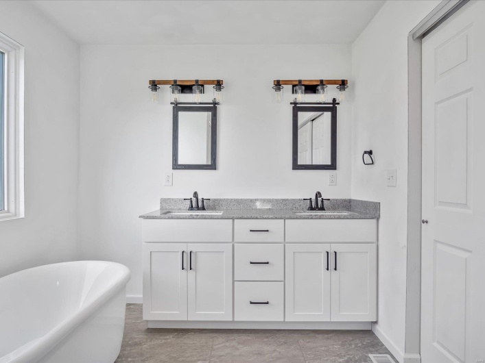 Bathroom featuring tile patterned floors, vanity, and a tub
