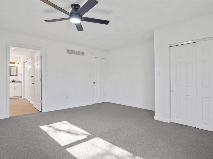 Unfurnished bedroom featuring ensuite bath, ceiling fan, sink, and carpet