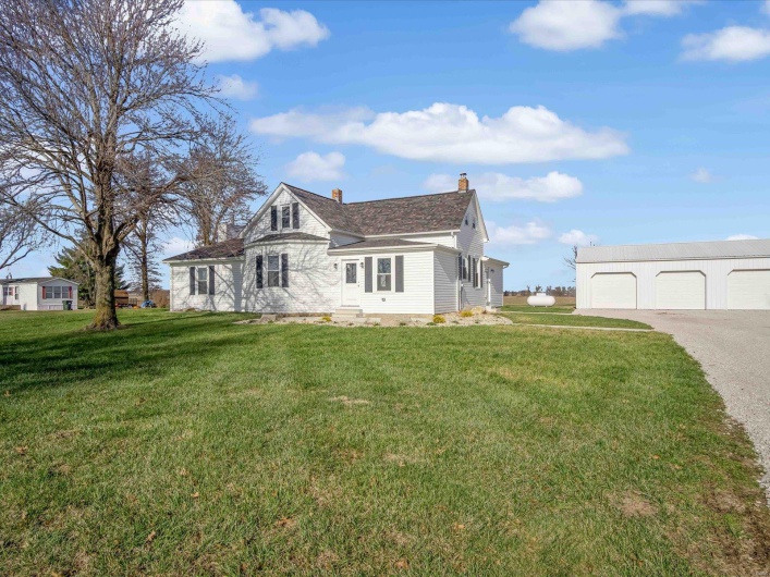 View of property exterior with a lawn, a garage, and an outbuilding